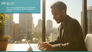 Business professional working on a laptop in a high-rise office with a city skyline view, representing marketing leadership through Fractional CMOs in Africa.